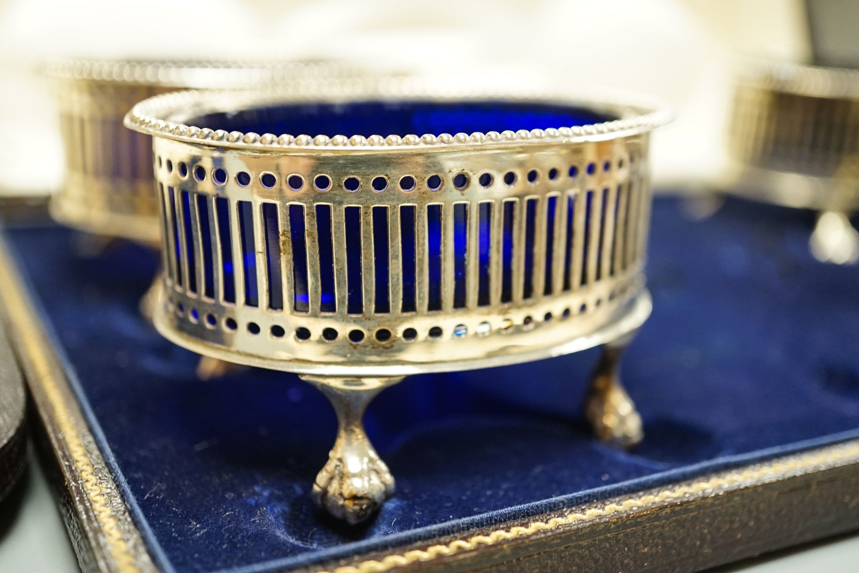 A cased pair of Victorian silver fish servers, London, 1856, together with a cased set of four George V pierced silver oval salts with cobalt blue glass liners (no spoons).